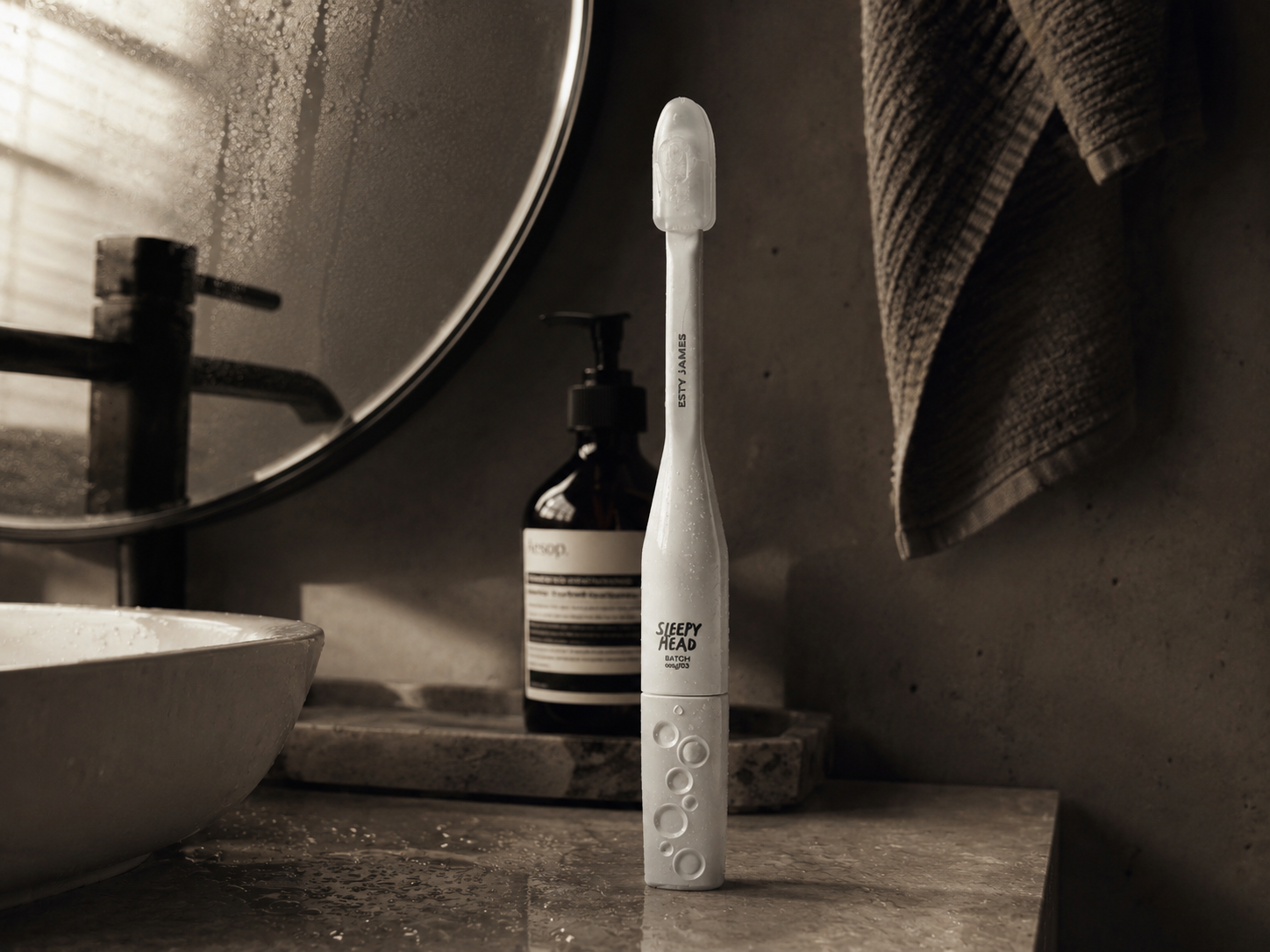 LUNA 3D+ sonic toothbrush standing on a stone bathroom counter beside an Aesop-style bottle and basin